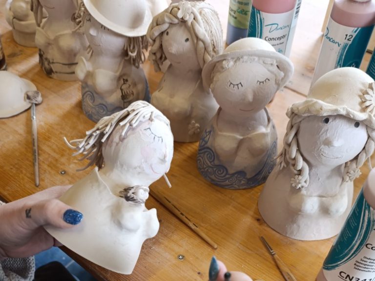 Töpferarbeiten von stilisierten Figuren mit verschiedenen Hüten und Frisuren.